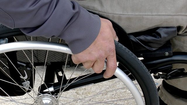 eine Hand ist hält das Rad eines Rollstuhls zum Vorwärtskommen.